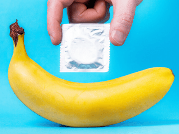 Person holding a condom above a banana